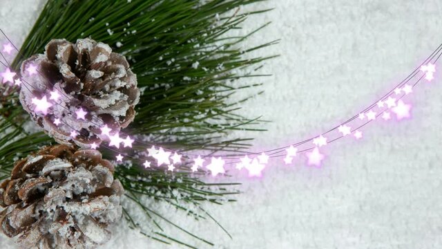 Animation of glowing fairy lights and pinecones christmas decorations