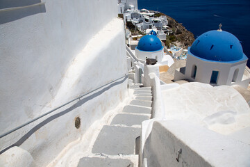 White staircase and wall leads to the orthodox church. Blue dome of the church against the blue sky and sea. Island Santorini is in Greece:  - 460392092