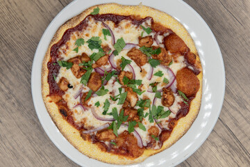 Overhead view of personal sized pizza with bbq chicken meat and plenty of toppings with a crispy crust