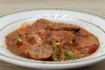 Bowl of salsiccia peperoni arrosto served in a bowl smothered in marinara sauce full of chopped sausage, peppers, and garlic