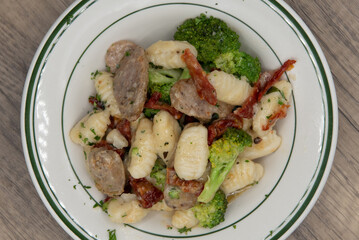 Overhead view of gnocchi alla barese Italian sausage, broccoli, and tomatoes served in a bowl and drenched in olive oil for a very hearty Italian meal