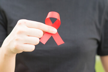 hand holding red ribbon of world aids day