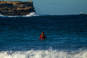 surfer from behind sitting in the ocean waiting for a wave to catch