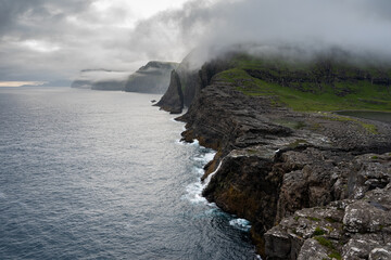 Beautiful aerial view of the Bøsdalafossur waterfall and Trælanípan magnificent landmarks in the Faroe Islands