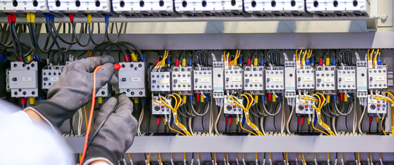 Fototapeta na wymiar Electricity and electrical maintenance service, Close-up circuit breaker has engineer using measuring equipment checking electric volt at terminal block and cable wiring main power distribution board.