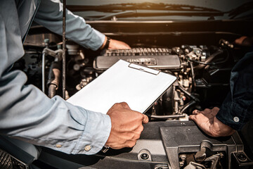 Car care maintenance and servicing, Hand mechanic using the checklist after change spare part car engine problem. Concepts of check and during periodic inspection service.