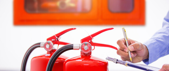 Naklejka premium Fire extinguisher, Engineer inspection checking pressure gauge level fire extinguisher tank with fire hose cabinet of protection and prevent emergency and safety rescue and fire alarm system training.