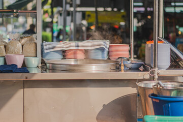Noodle bowls and hot soup pot  in food cabinet at street food shop.	