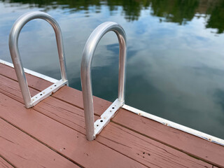 A swim ladder on an old dock by the lake.