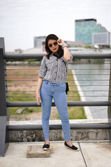 Young Beautiful Asian Woman Wearing Plaid Shirt And Blue Jeans Posing Outdoors