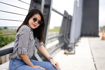 Fototapeta premium Young Beautiful Asian Woman Wearing Plaid Shirt And Blue Jeans Posing Outdoors