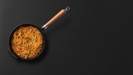 Fototapeta na wymiar Noodles in pan on black background top view stock photograph with copy space free image