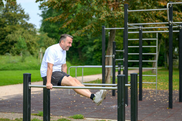 Obraz premium Senior man working out on outdoor parallel bars