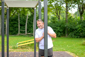 Happy healthy man standing in an outdoors sports area