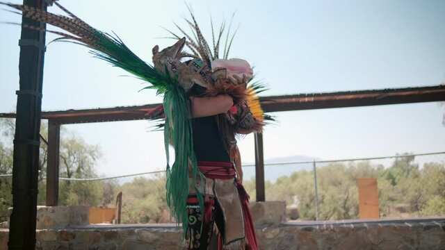 Dancer performing dance of pre-Hispanic culture with bright sky as background