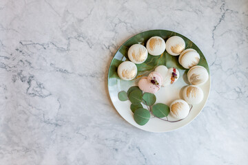 White macaroons are on a plate. Delicious light cookies on a plate on a light background. Bakery