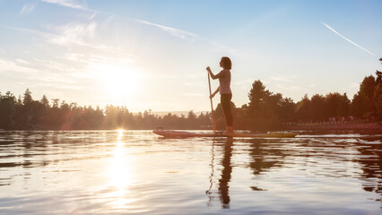 Adventurous Caucasian Adult Woman Paddling on a Stand up Paddle Board in water at a city park....