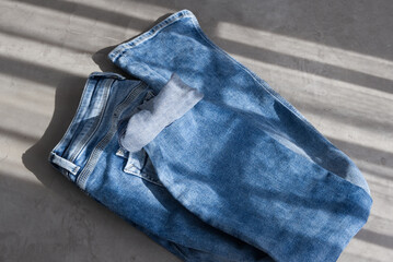 a blue light folded jeans on a grey background. Sunlight