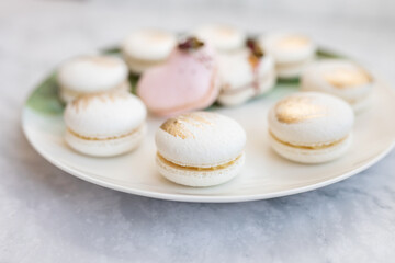 White macaroons are on a plate. Delicious light cookies on a plate on a light background. Bakery