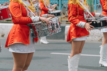 Young girls drummer in red vintage uniform at the parade. Street performance of festive march of...