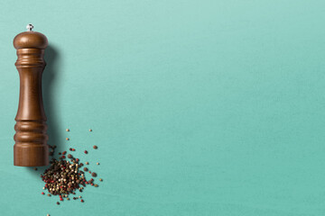 Pepper grinder with pepper on clean background with space for text