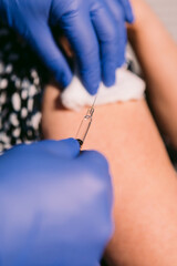 Nurse disinfects an older woman's arm with cotton to inject a vaccine