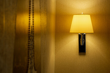 Modern sconce with turned on bulb under lampshade hanging on wall.