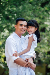 Portrait of a happy asian father holding his daughter in his hands