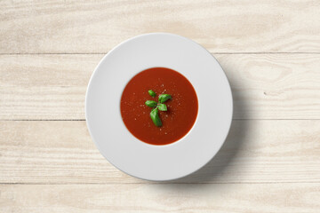 Tomato soup in white plate on wooden background