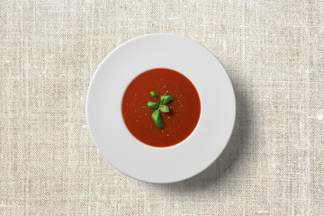 Tomato soup in white plate on wooden background