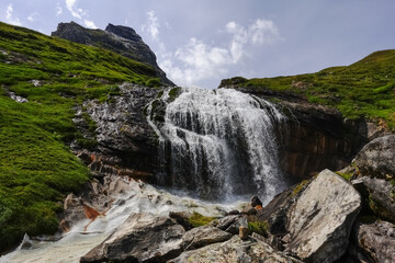 Obraz premium gorgeous waterfall over high rocks while hiking to the top of a mountain