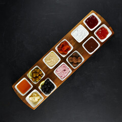 different sauces in small white plates, ketchup, mayonnaise, mustard, garlic, olives