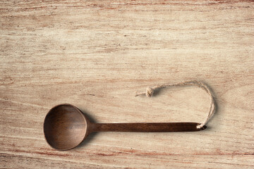 Wooden cooking  spoon horizontally lying on clean wooden table top view shot, with space for text.