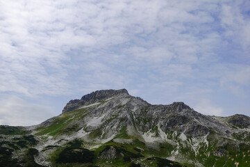 high rocky mountain with little bit snow on the top with soft clouds