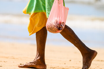 person on the beach with fish in a bag