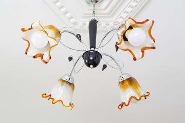 The four-armed ceiling lamp is made of glass in the shape of a flower. 