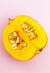 In the center on a pink background lies half of a small pumpkin