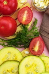 Top view of fresh red tomatoes, sliced zucchini and dill