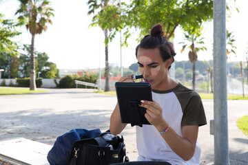 Obraz premium young latina transsexual woman is in a park where she is going to start doing her make-up for her big change from boy to girl. Concept of diversity, transgender, and freedom of homosexual expression.