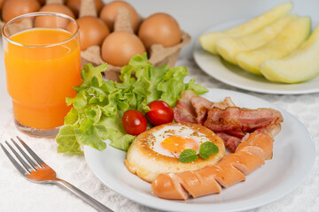 Fried egg bread bacon fried sausage fresh vegetable with orange juice, Homemade breakfast.