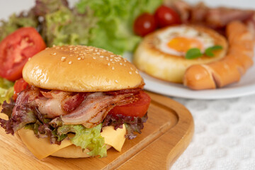 Closeup of Bacon cheeseburger and fried egg bun with fresh vegetable breakfast.