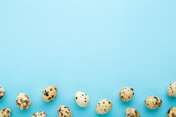 Quail eggs on light blue table background. Pastel color. Empty place for text. Closeup. Top down view.