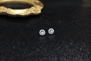 Diamonds with white gold earring setting on black satin fabric. Fine Jewelry photo set for engagement or wedding ceremony