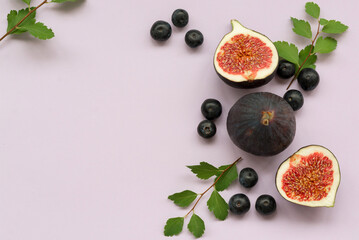 Flat lay of ripe cut fruits  - figs and blueberries on an light purple background. Top view, copy...