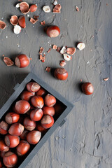 Food background with hazelnuts on a dark gray slate, stone or concrete table. Top view. A lot of nuts in a wooden box.Healthy selection of various super-dishes.