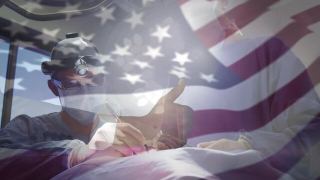 Animation of flag of united states of america waving over surgeons in operating theatre