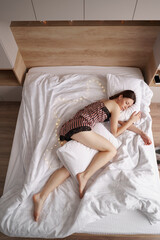 Obraz na płótnie Canvas Caucasian woman sleeping in bed. Lady enjoys fresh soft bedding linen and mattress in bedroom