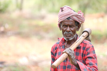 Indian old farmer holding a hoe