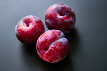 Ripe red plums on a dark background