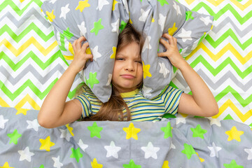 The child is lying in bed and does not want to get up and go to school.